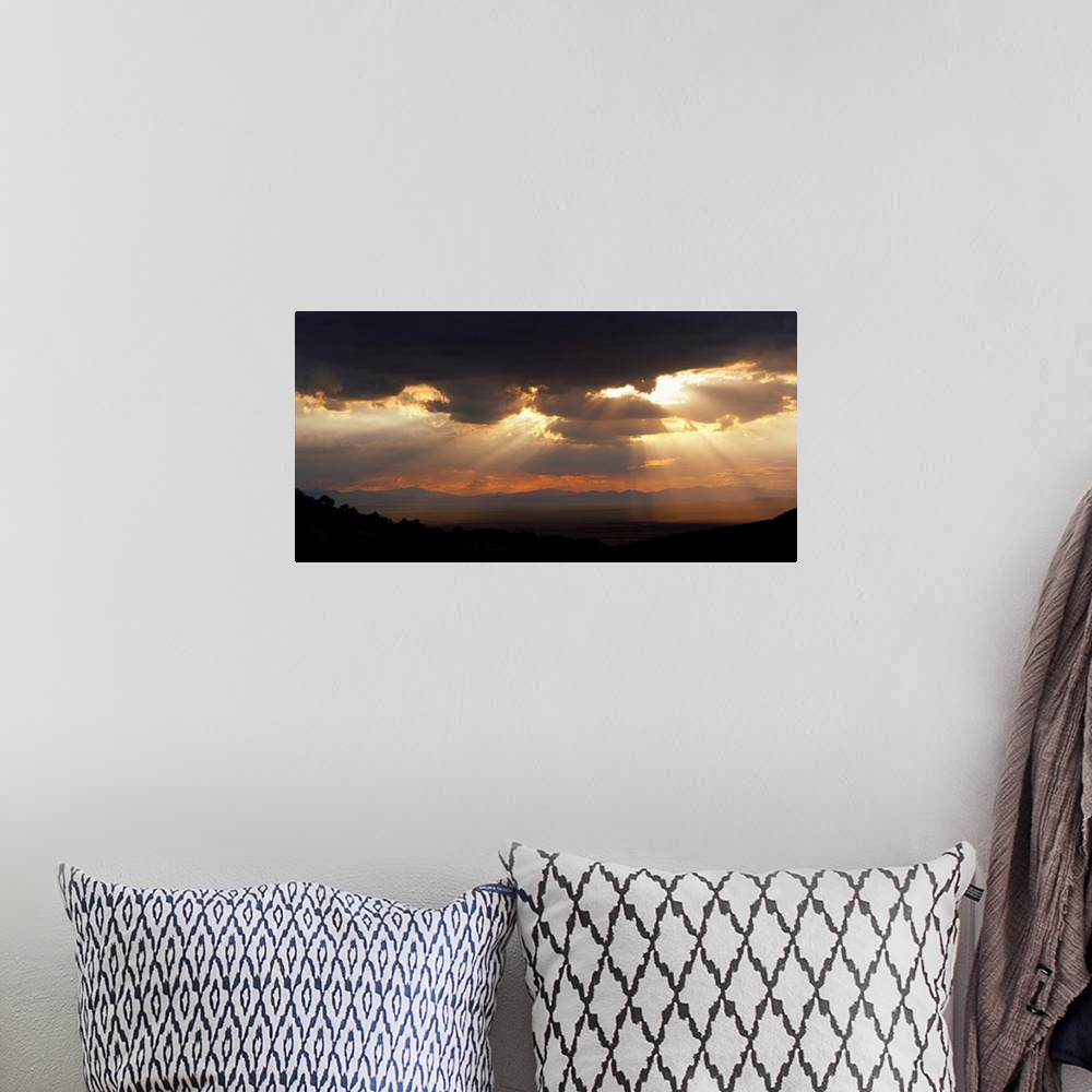 A bohemian room featuring Horizontal, large photograph of sunlight beaming through a sky full of huge, dark clouds, over th...