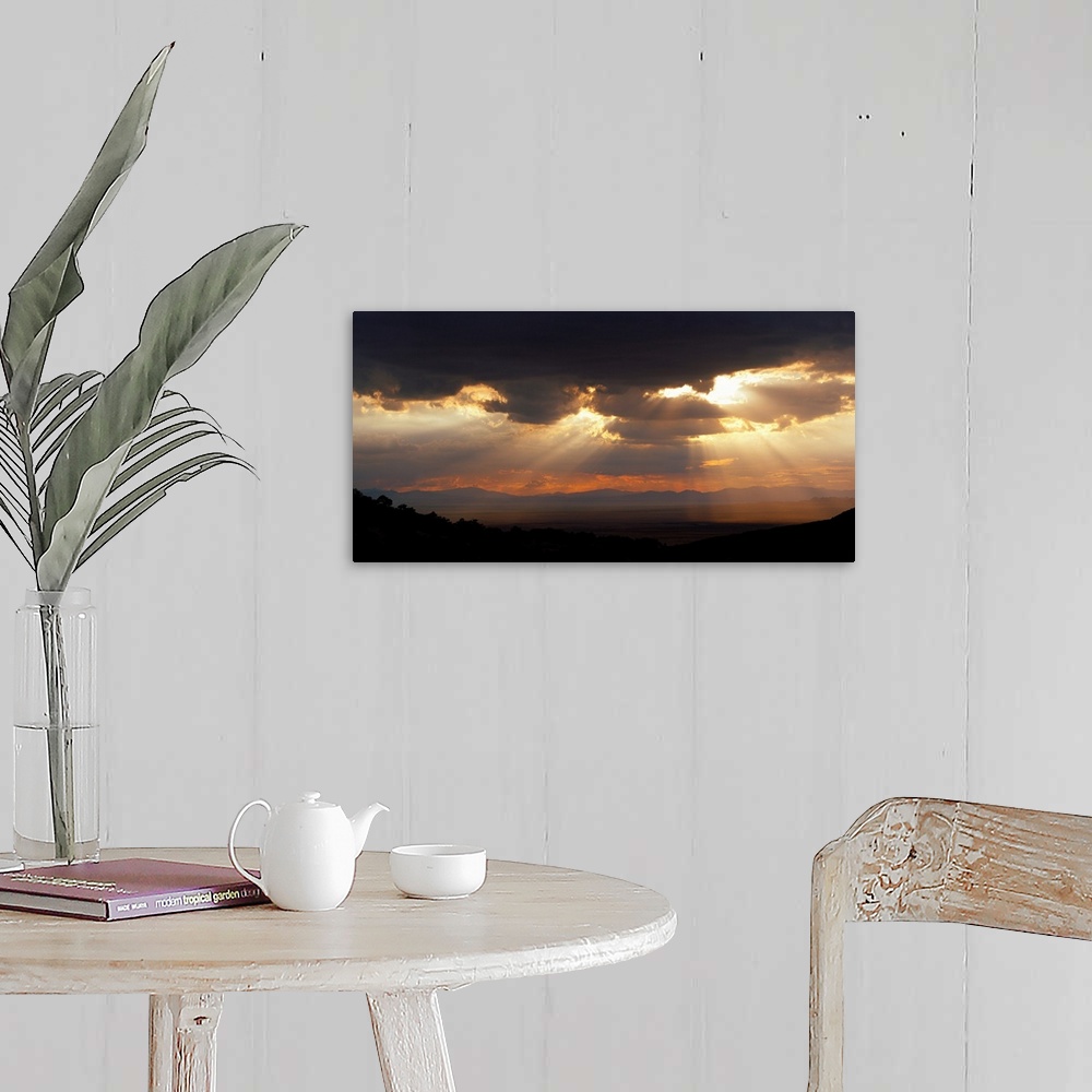 A farmhouse room featuring Horizontal, large photograph of sunlight beaming through a sky full of huge, dark clouds, over th...