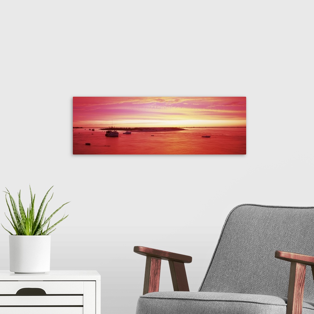 A modern room featuring Panoramic image of boats floating in a harbor in Massachusetts while a beautiful sky is painted b...