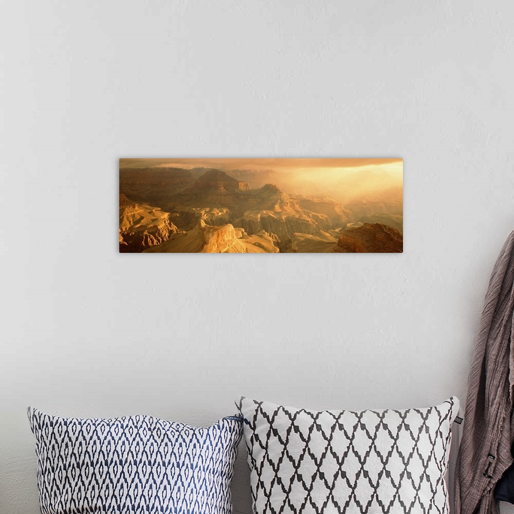 A bohemian room featuring Panoramic photo on canvas of the Grand Canyon bath in warm sunlight from a rising sun.