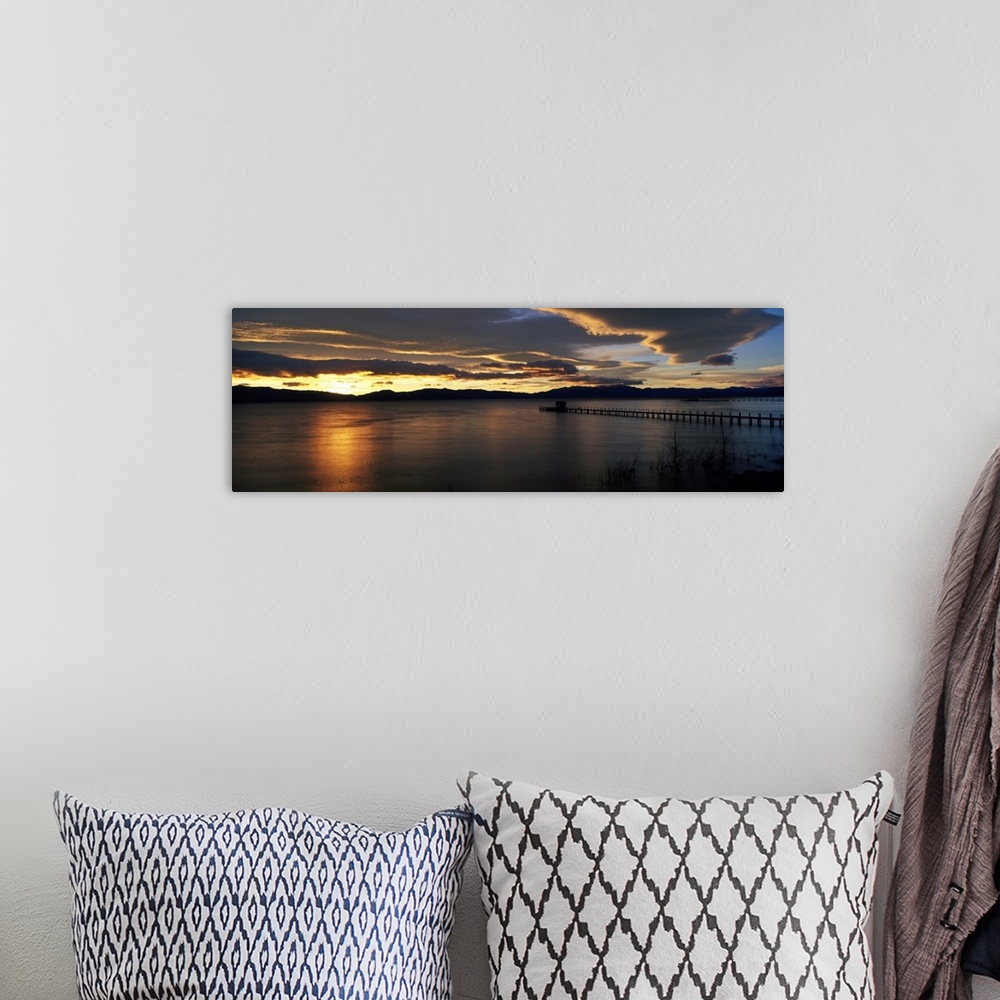 A bohemian room featuring Panoramic photograph of pier stretching into water at dawn.  The sky is dark and cloudy.