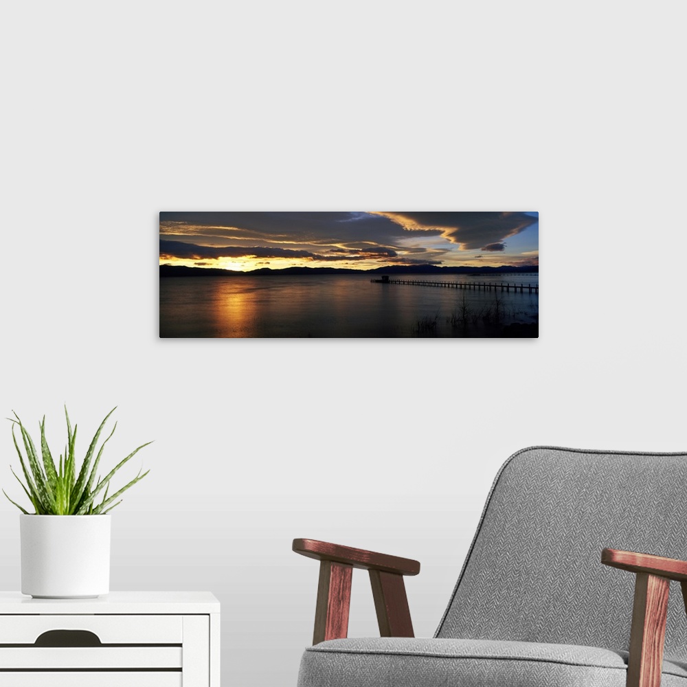 A modern room featuring Panoramic photograph of pier stretching into water at dawn.  The sky is dark and cloudy.