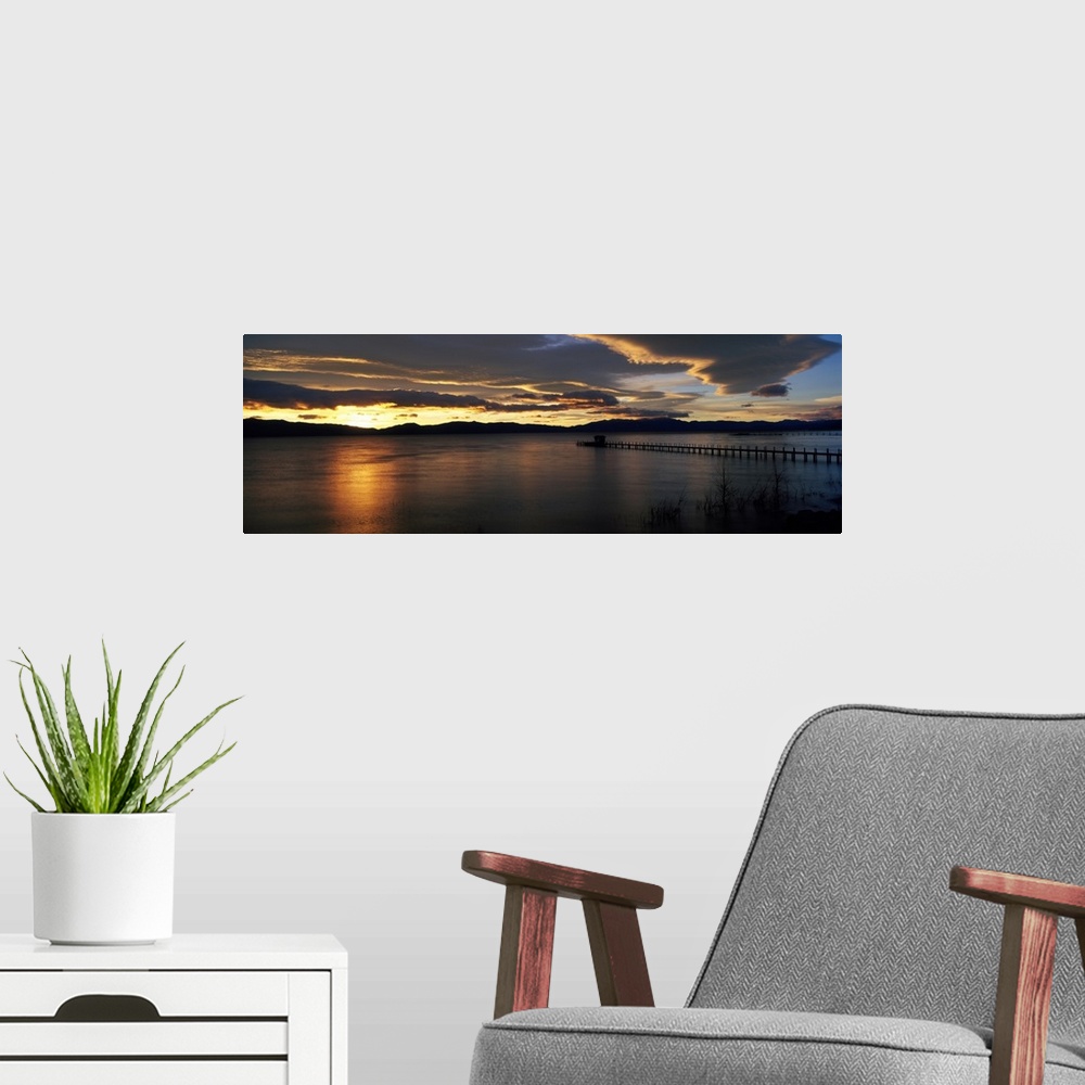 A modern room featuring Panoramic photograph of pier stretching into water at dawn.  The sky is dark and cloudy.