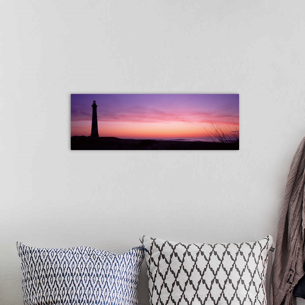 A bohemian room featuring A panoramic canvas with a pastel colored sky with a light house towering over the sandy beach on ...