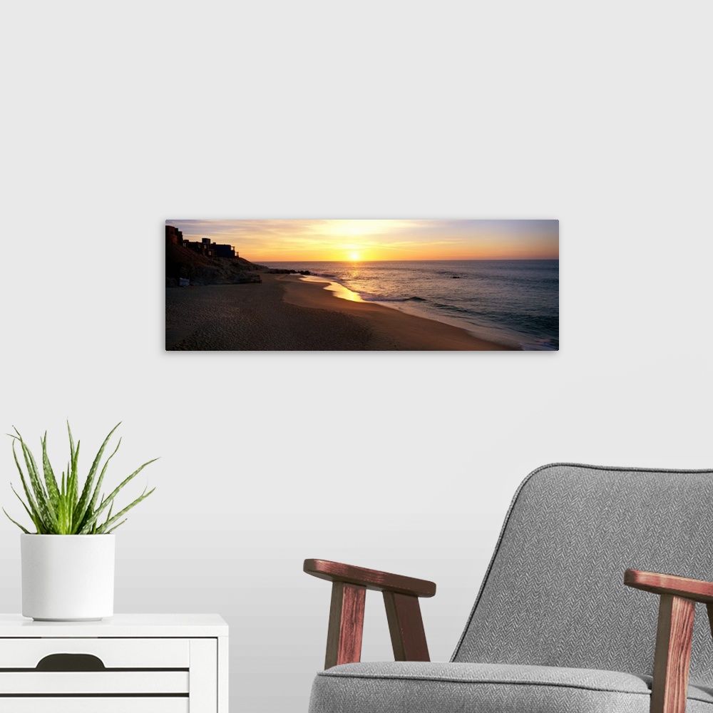 A modern room featuring Panoramic photo of the sun rising over the beach in Los Cabos, Mexico.