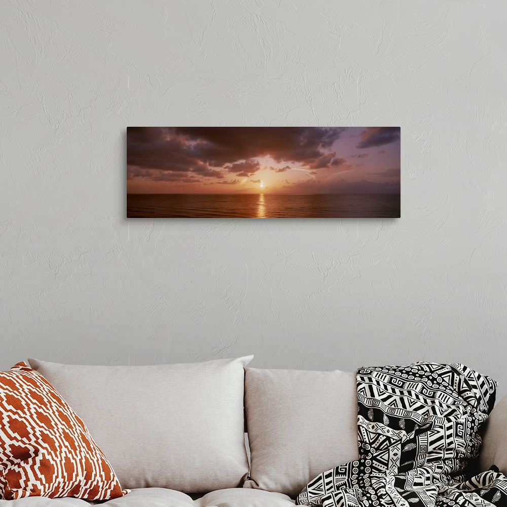 A bohemian room featuring Panoramic photograph of ocean at dawn under a cloudy sky.