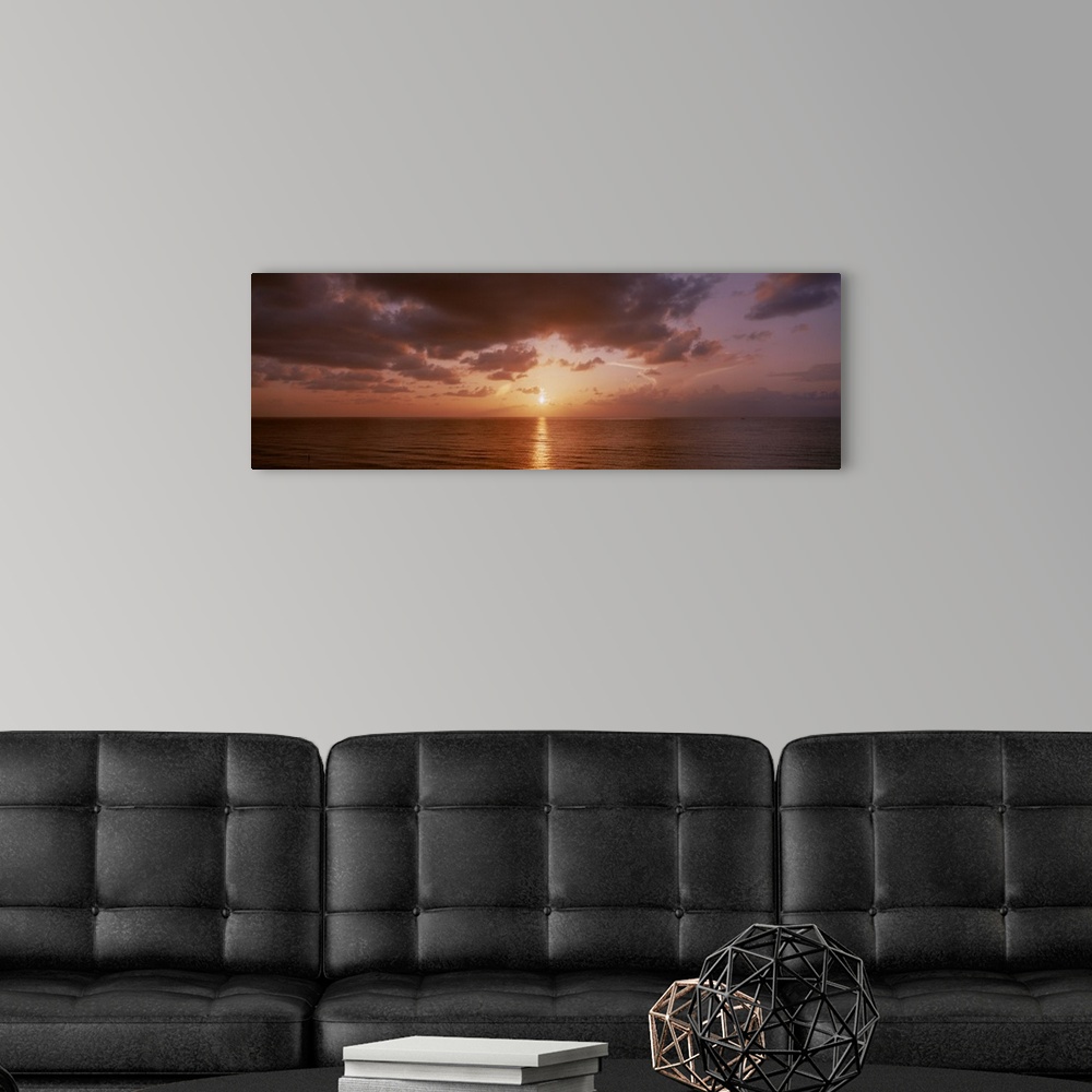 A modern room featuring Panoramic photograph of ocean at dawn under a cloudy sky.