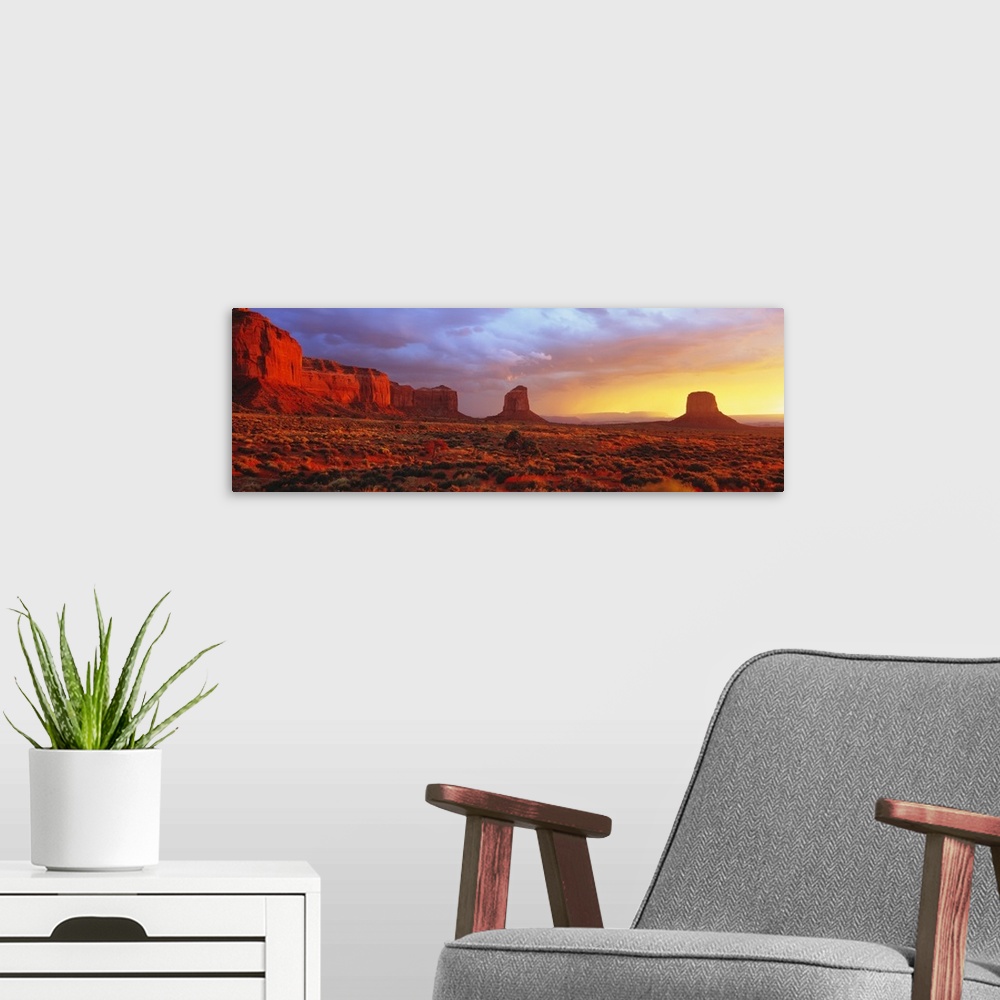 A modern room featuring Large panoramic canvas of a desert scene with steep rugged terrain and rock structures at sunrise.
