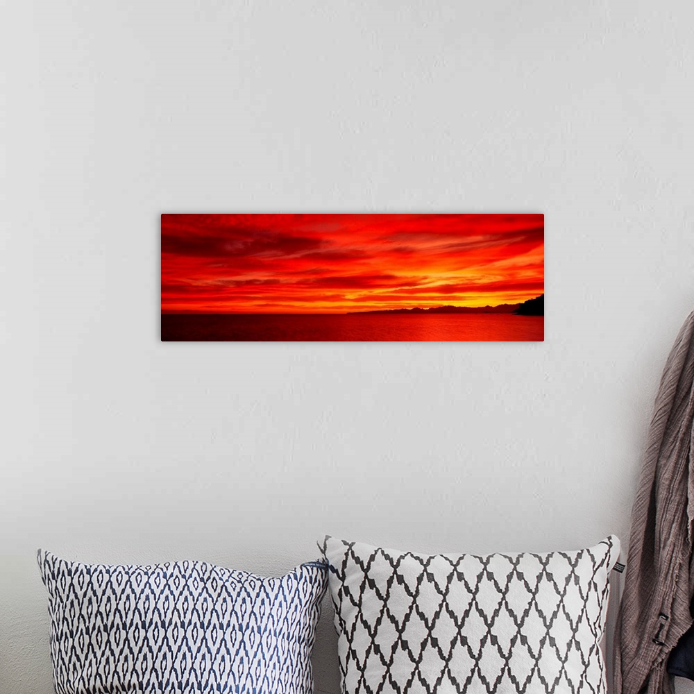 A bohemian room featuring Large wall image of a deep warm sunset over the ocean with a little strip of land on the right si...