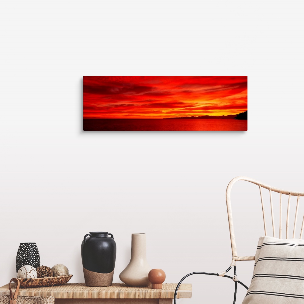 A farmhouse room featuring Large wall image of a deep warm sunset over the ocean with a little strip of land on the right si...