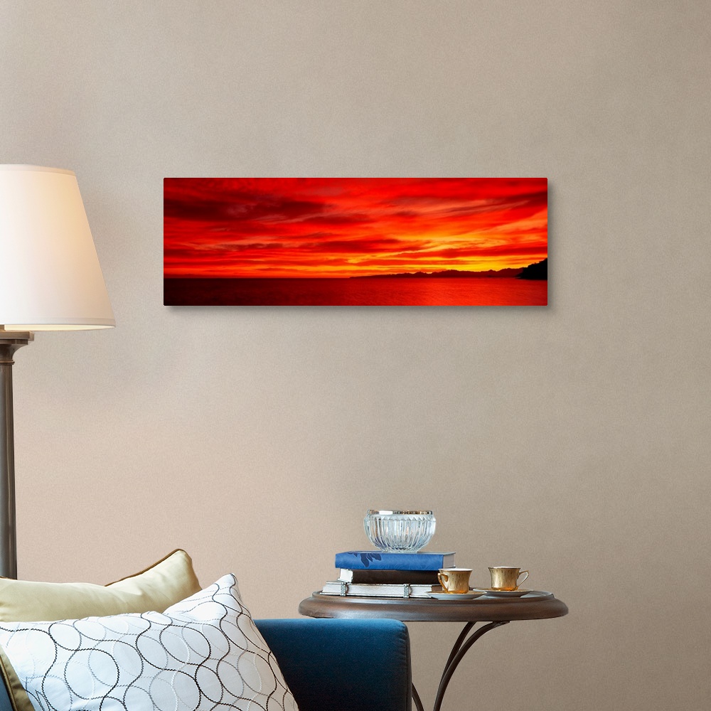 A traditional room featuring Large wall image of a deep warm sunset over the ocean with a little strip of land on the right si...