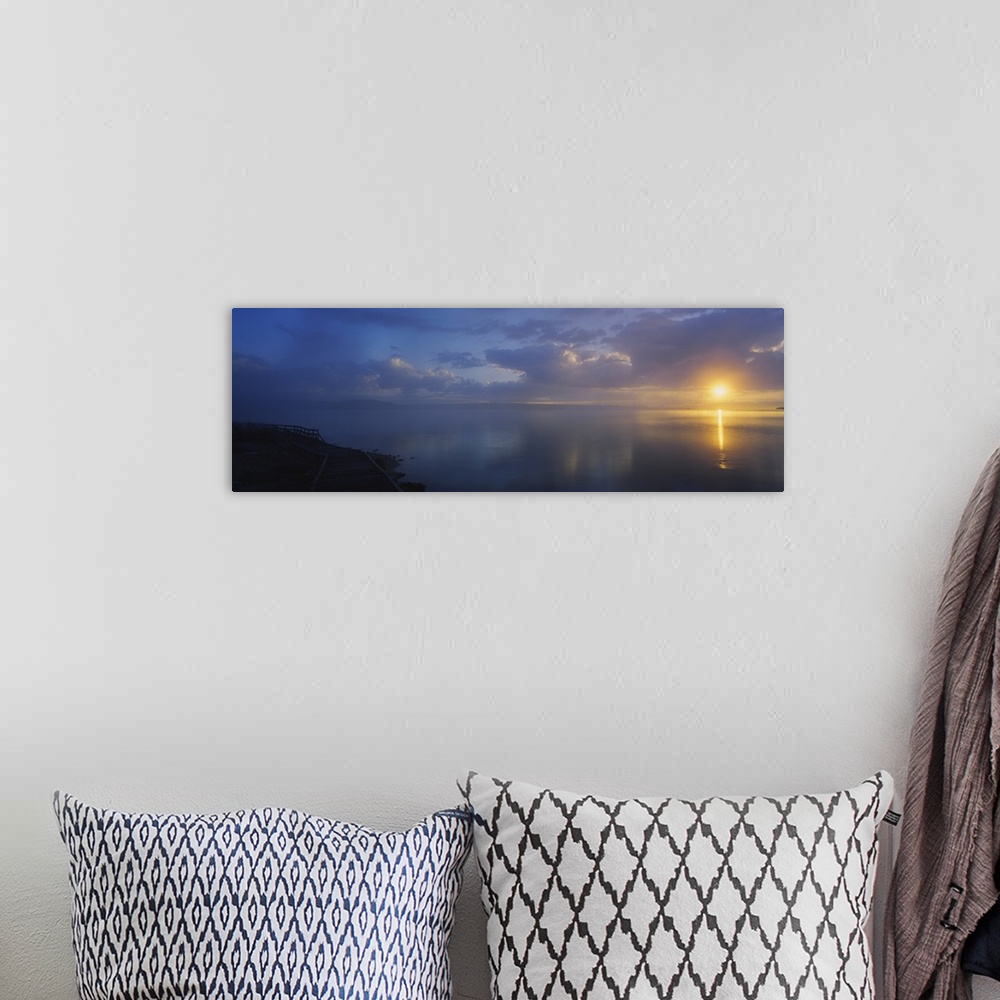 A bohemian room featuring Panoramic photograph of walkway alongside ocean at dawn under a cloudy sky.