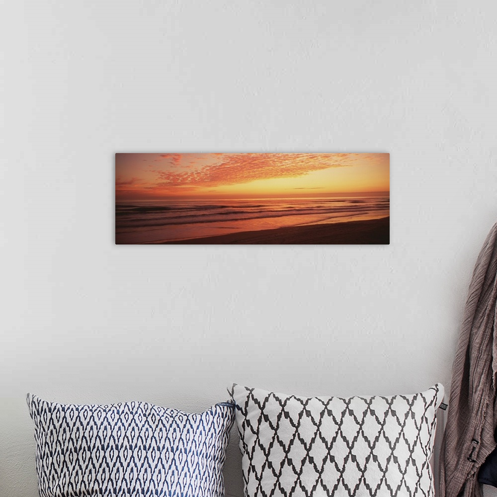 A bohemian room featuring Large, wide angle photograph of a golden sunrise over the Atlantic Ocean, at the shoreline of Day...