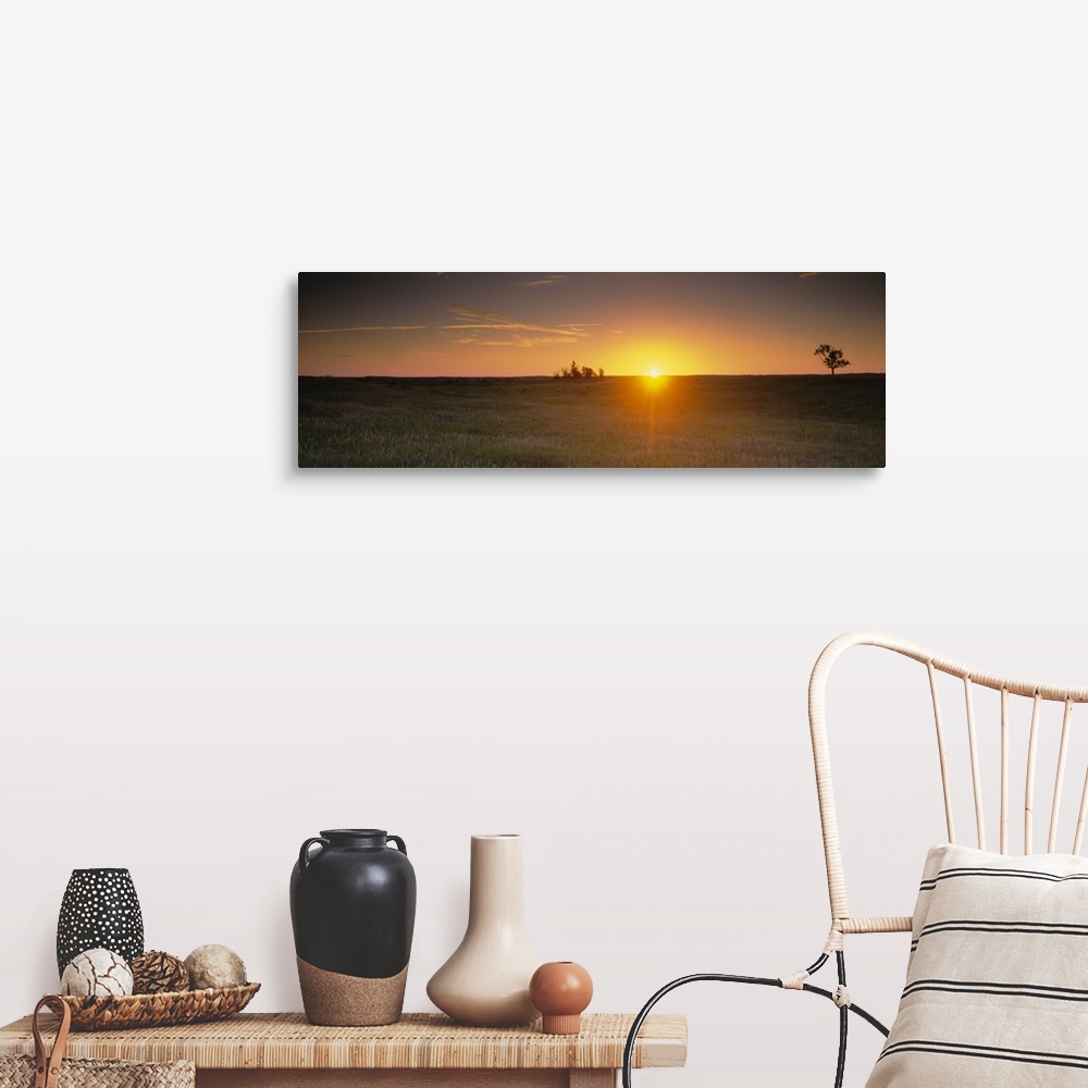 A farmhouse room featuring Panoramic picture taken of the sun rising just over the horizon and onto a massive grass plain.