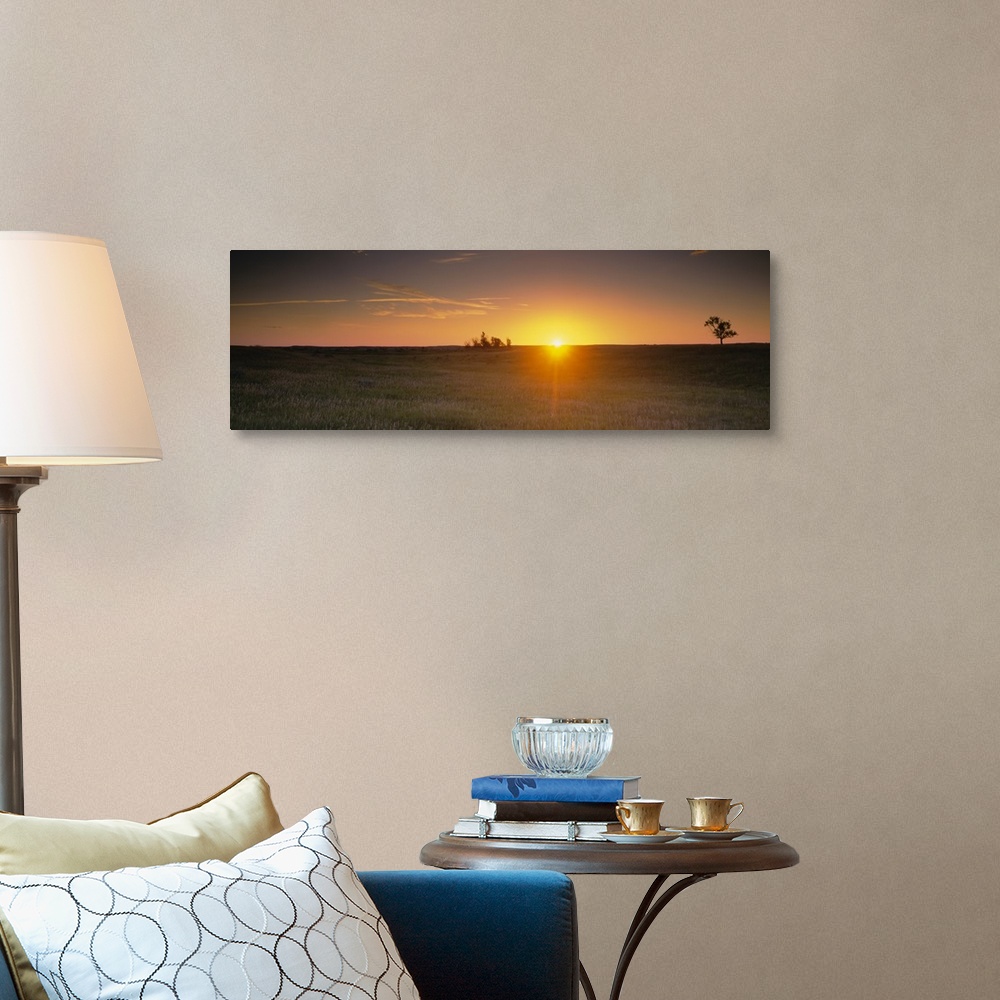 A traditional room featuring Panoramic picture taken of the sun rising just over the horizon and onto a massive grass plain.