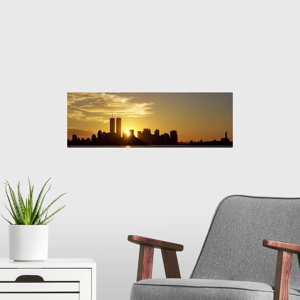A modern room featuring Panoramic photo of the sun rising right between two buildings in the silhouetted New York skyline...