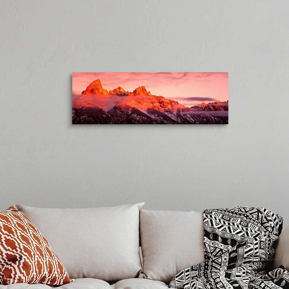 A bohemian room featuring The sun rises on rugged mountains casting a warm hue of sunlight over the tops of them with darkn...