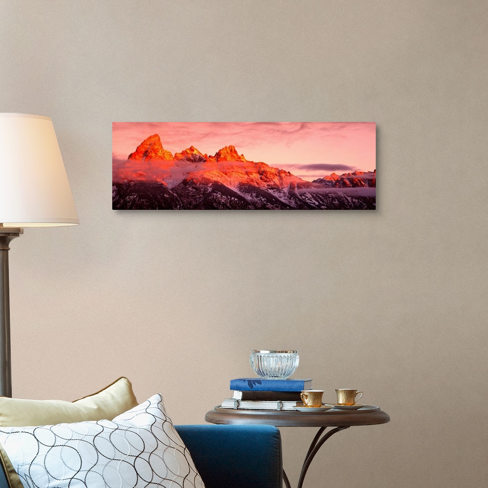 A traditional room featuring The sun rises on rugged mountains casting a warm hue of sunlight over the tops of them with darkn...