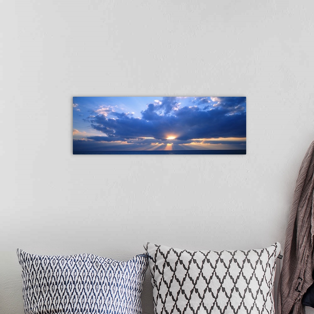 A bohemian room featuring Panoramic photograph of the sun peaking through large, fluffy clouds as it sets over the Gulf of ...