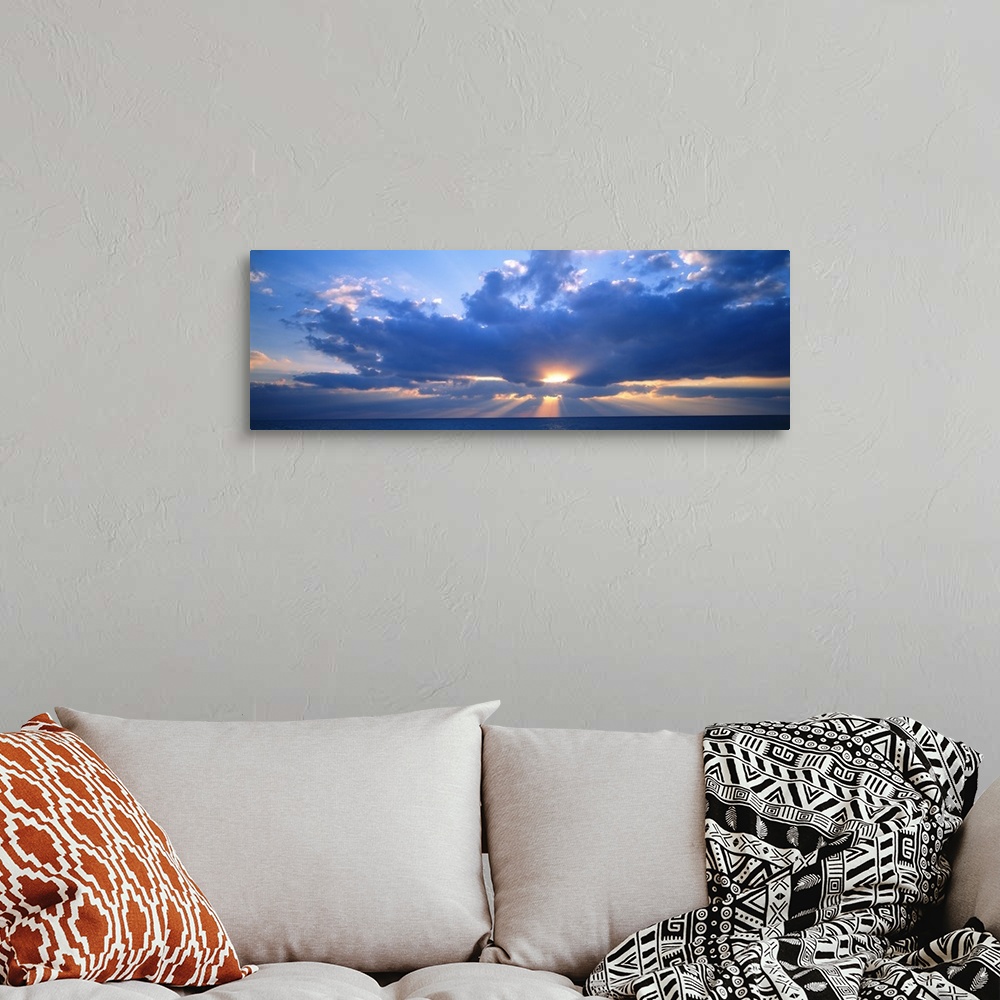 A bohemian room featuring Panoramic photograph of the sun peaking through large, fluffy clouds as it sets over the Gulf of ...