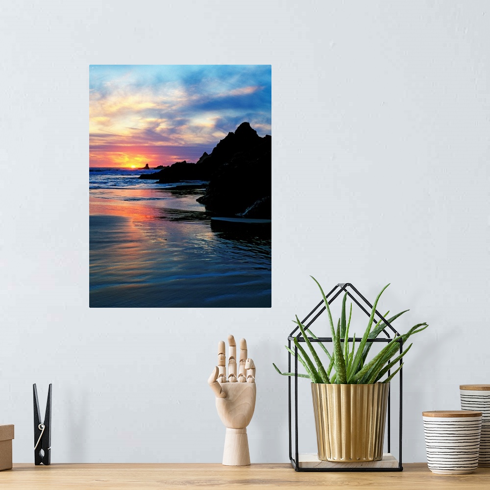 A bohemian room featuring Sun below the horizon in a seascape with a rocky beach and waves.