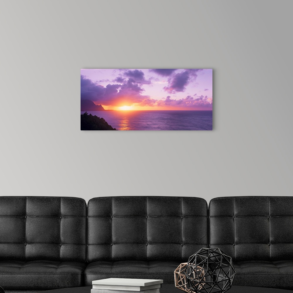 A modern room featuring Sun setting on the ocean horizon creating a pastel-colored sky in the evening in Hawaii. Large la...