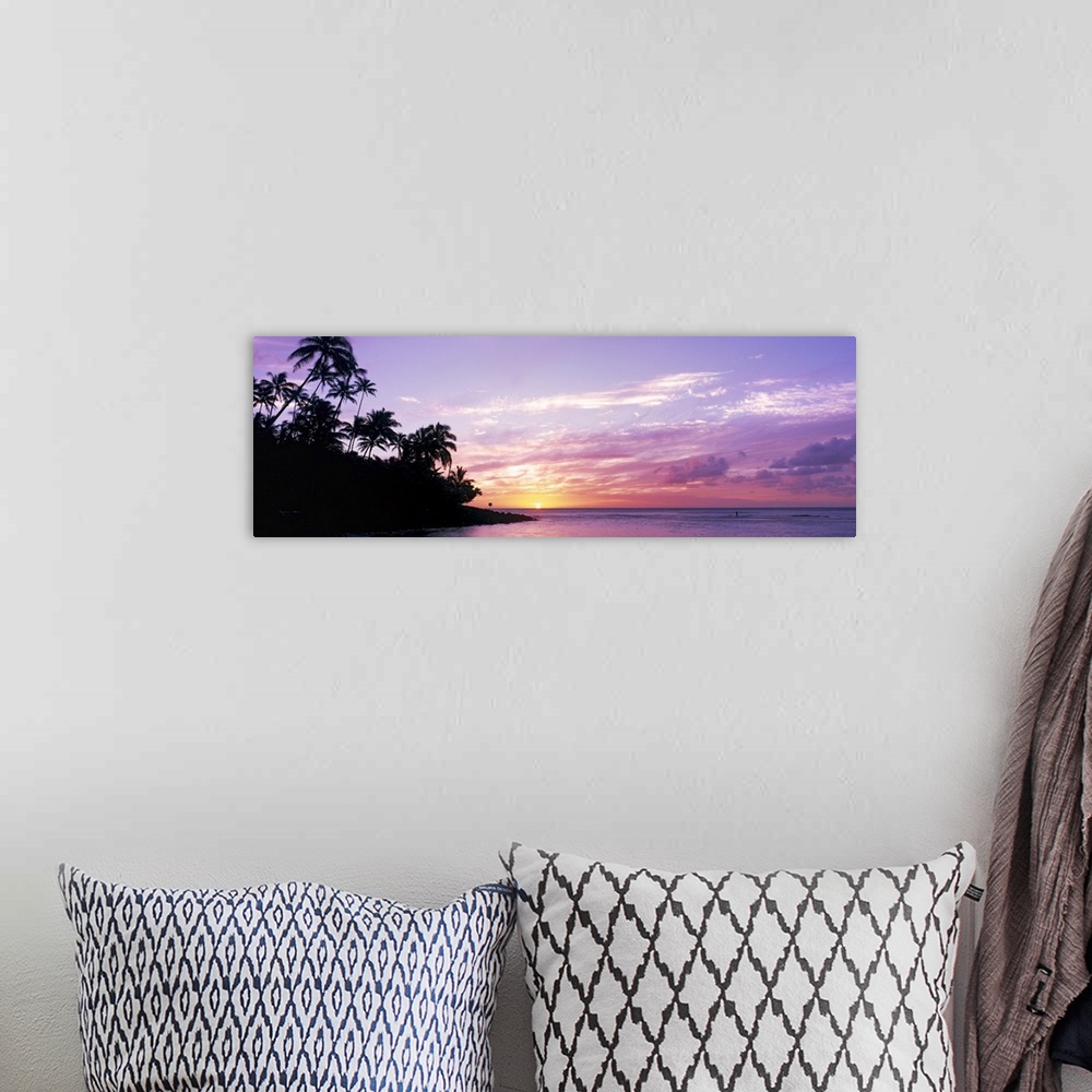 A bohemian room featuring Panoramic photograph displays the sun in the far distance as it begins to set over an island fill...