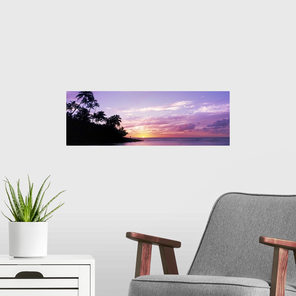 A modern room featuring Panoramic photograph displays the sun in the far distance as it begins to set over an island fill...
