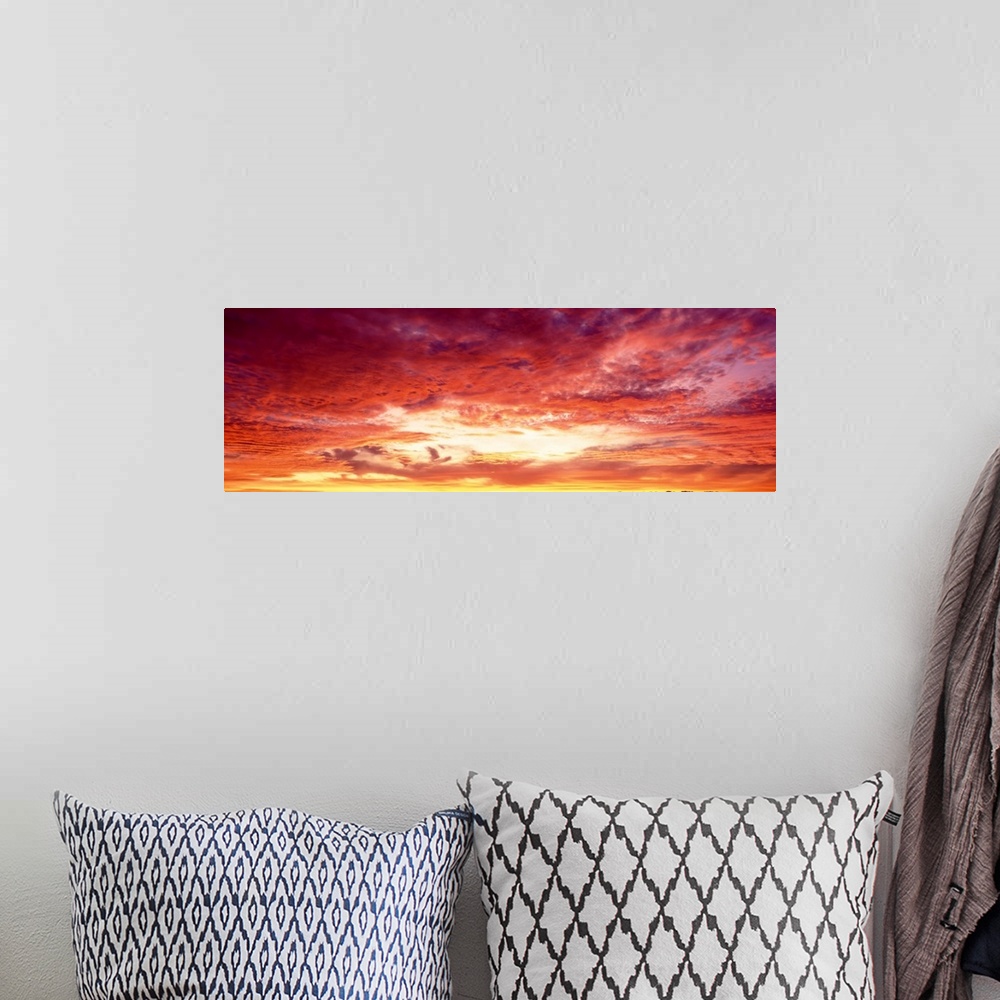A bohemian room featuring Panoramic photograph of a beautiful sunset sky with warm colored clouds gathered around the sun.