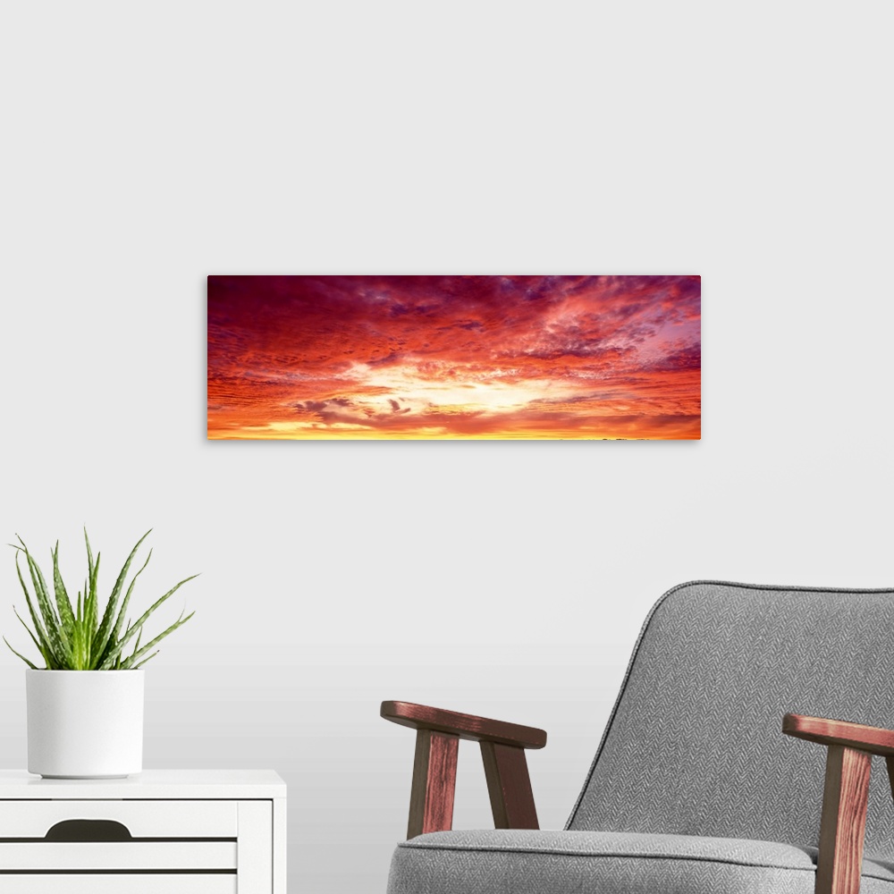 A modern room featuring Panoramic photograph of a beautiful sunset sky with warm colored clouds gathered around the sun.