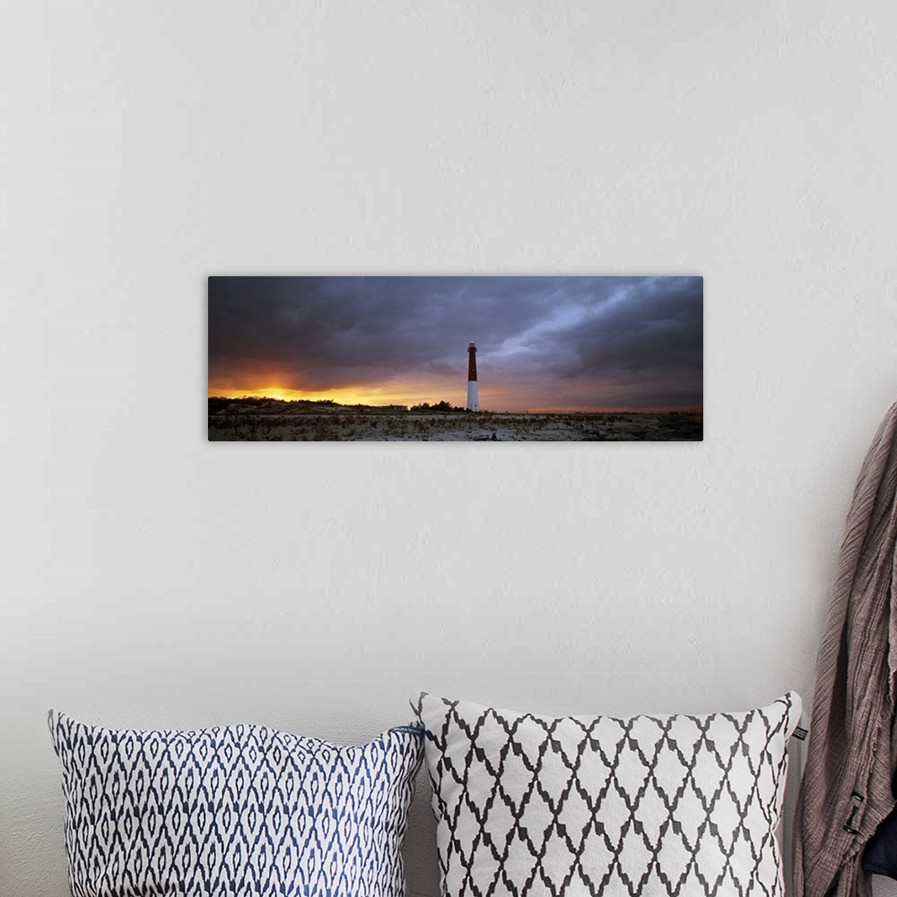 A bohemian room featuring Panoramic photograph of watchtower on beach at dusk.  The sky is cloudy and the sun is barely vis...