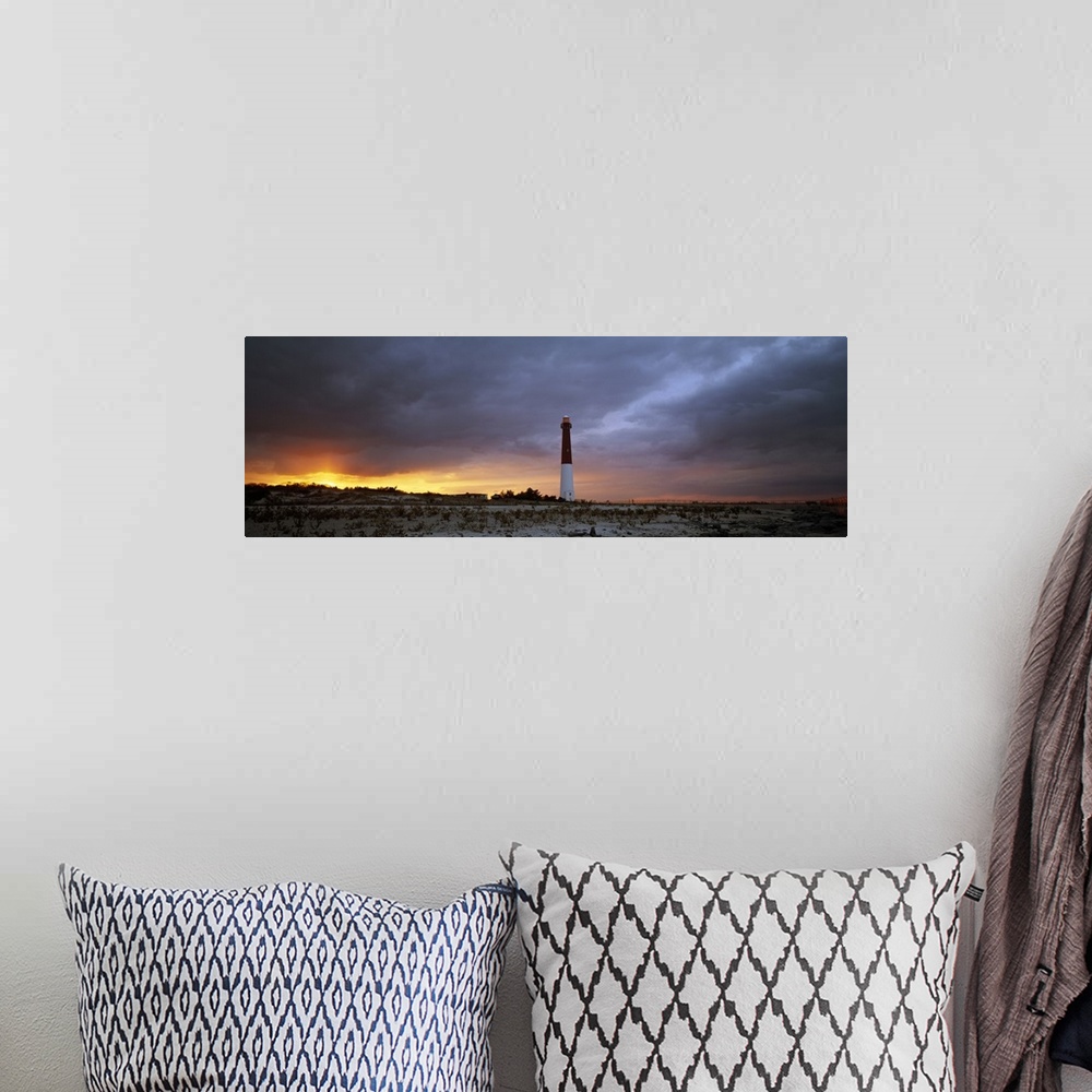 A bohemian room featuring Panoramic photograph of watchtower on beach at dusk.  The sky is cloudy and the sun is barely vis...