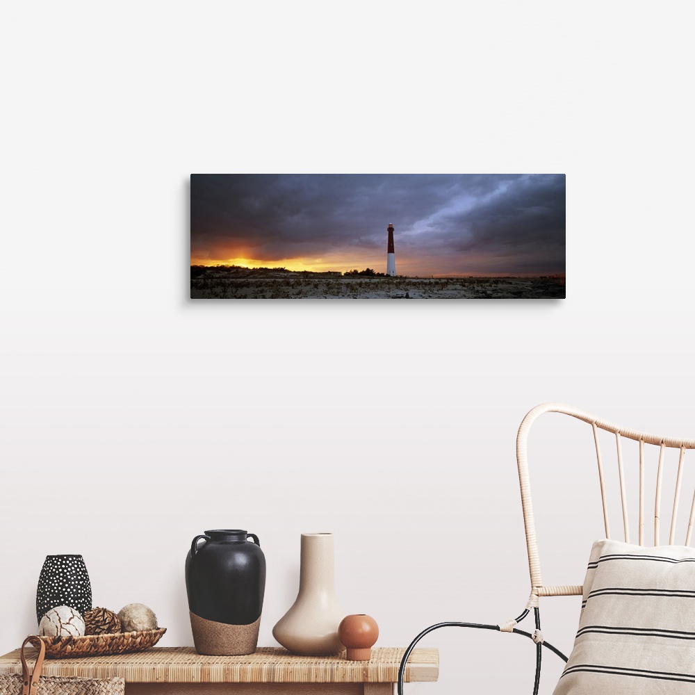 A farmhouse room featuring Panoramic photograph of watchtower on beach at dusk.  The sky is cloudy and the sun is barely vis...