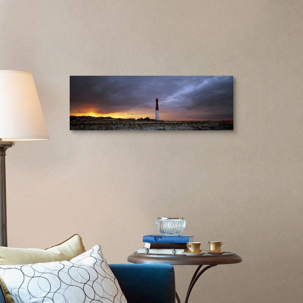 A traditional room featuring Panoramic photograph of watchtower on beach at dusk.  The sky is cloudy and the sun is barely vis...