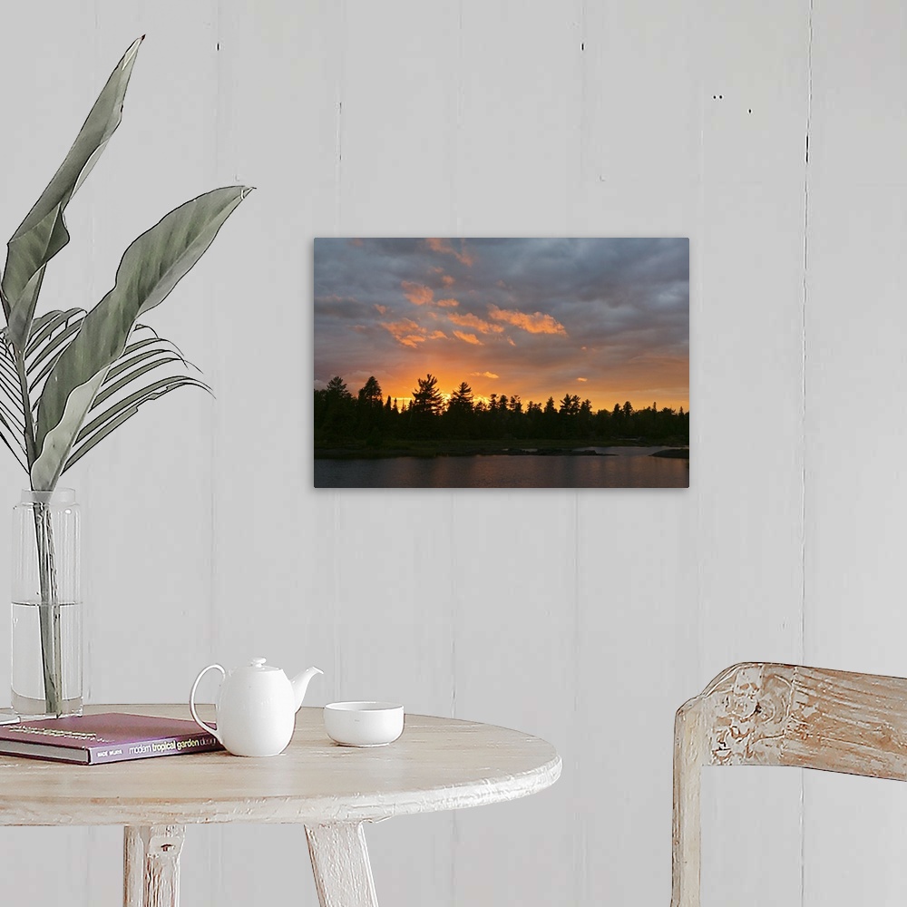 A farmhouse room featuring A beautiful picture taken of a thick forest from across a lake with a sun setting behind it silho...