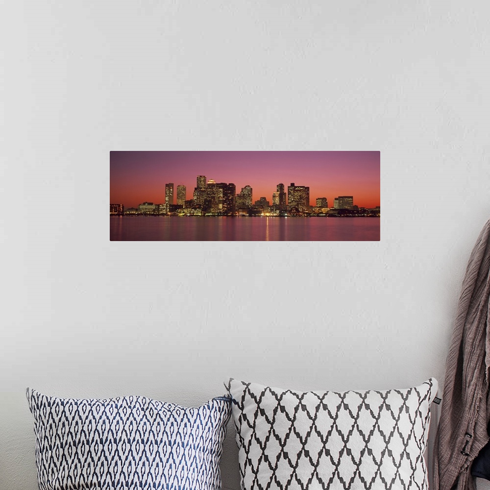 A bohemian room featuring A Massachusetts city lights up at twilight over its blurred reflection in the waters of the bay.