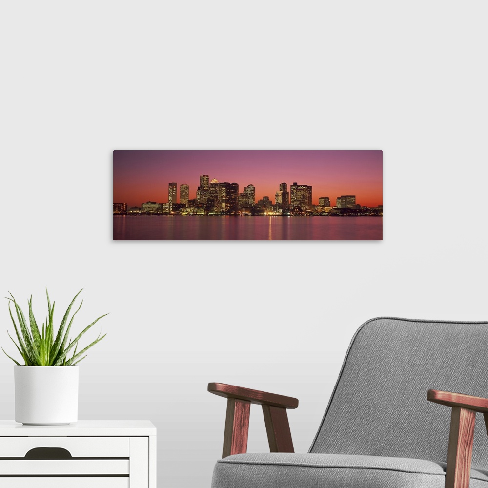A modern room featuring A Massachusetts city lights up at twilight over its blurred reflection in the waters of the bay.