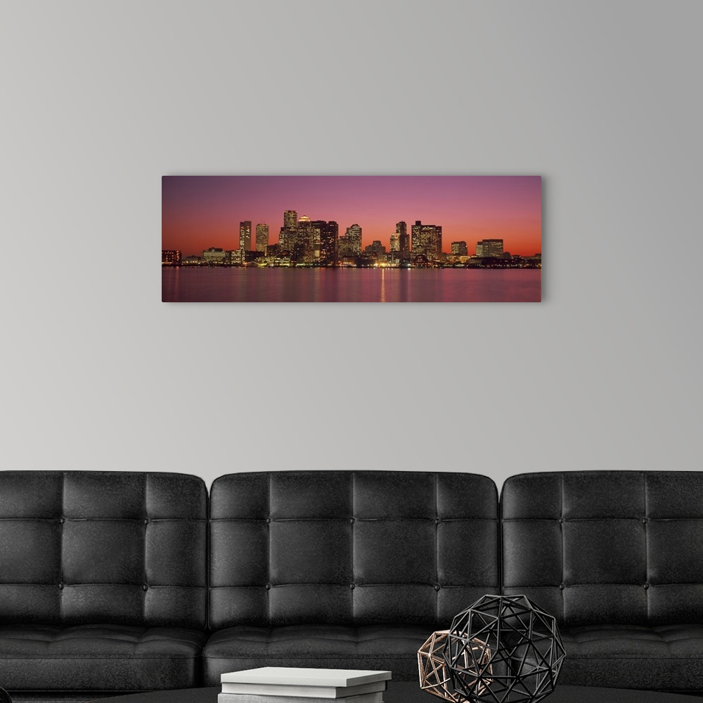 A modern room featuring A Massachusetts city lights up at twilight over its blurred reflection in the waters of the bay.