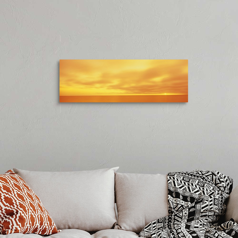 A bohemian room featuring Panoramic photograph of calm wave less ocean under a cloudy sky.