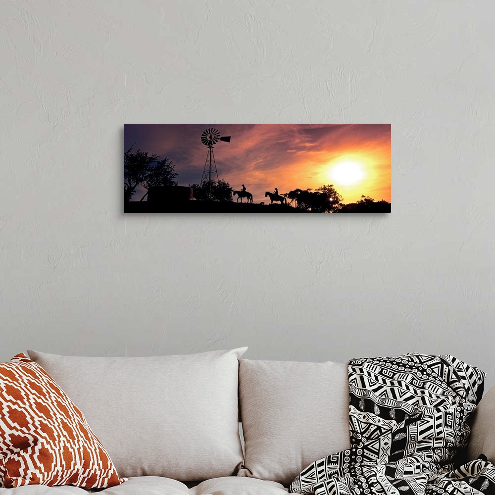 A bohemian room featuring This panoramic photograph depicts an evening moment on ranch hill side as horseback riders pass b...