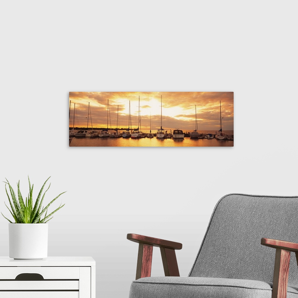 A modern room featuring Horizontal panorama of a row of sailboats with their sails down, docked at a port on a lake at su...