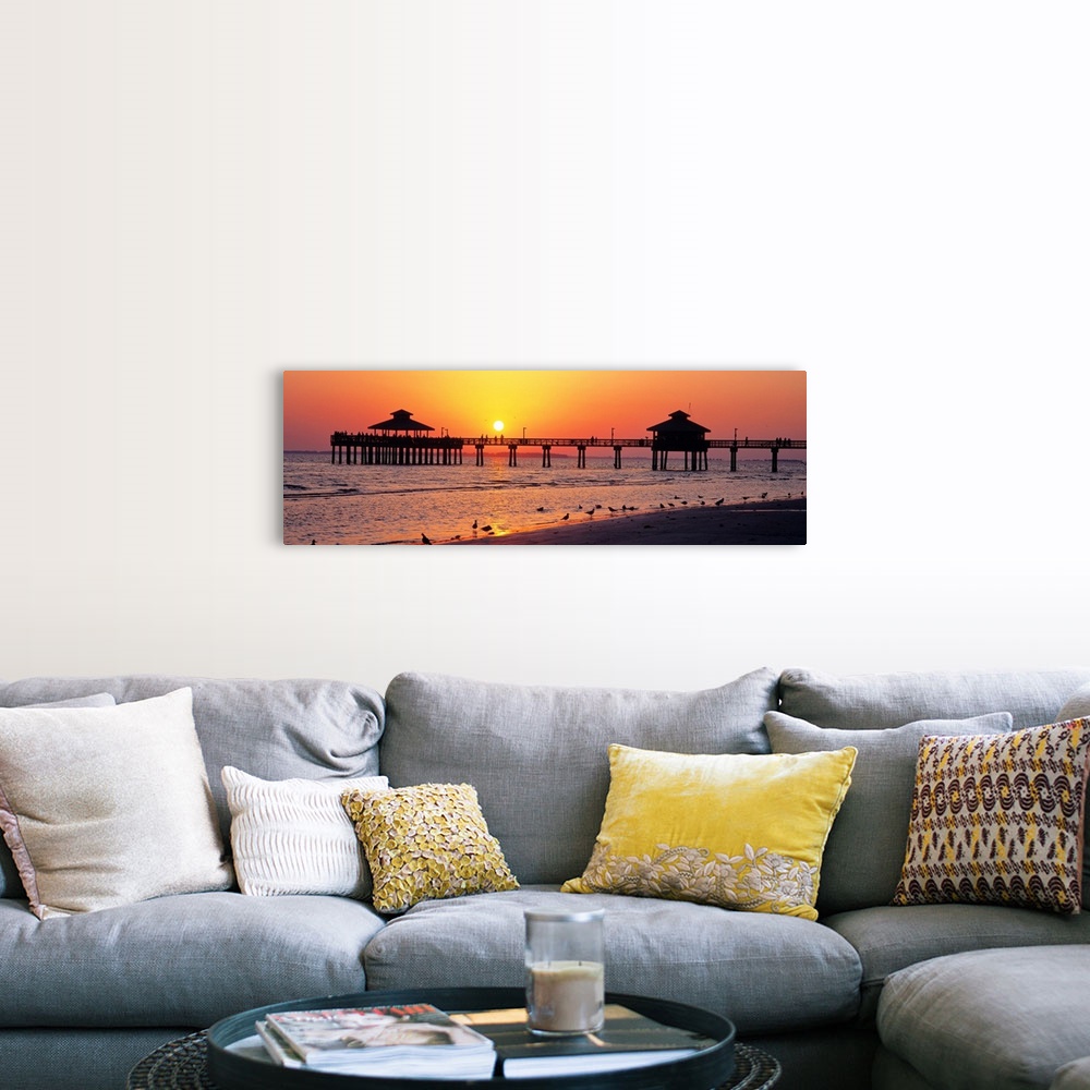 A farmhouse room featuring Pier and board walk with shore birds gathered in the foreground as the sun sinks in the sky.
