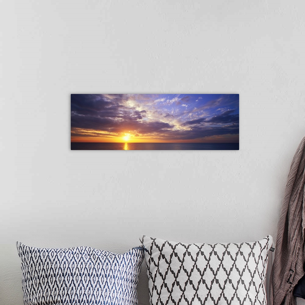 A bohemian room featuring This large panoramic picture was taken of a sunset about to hit the horizon over the ocean with c...