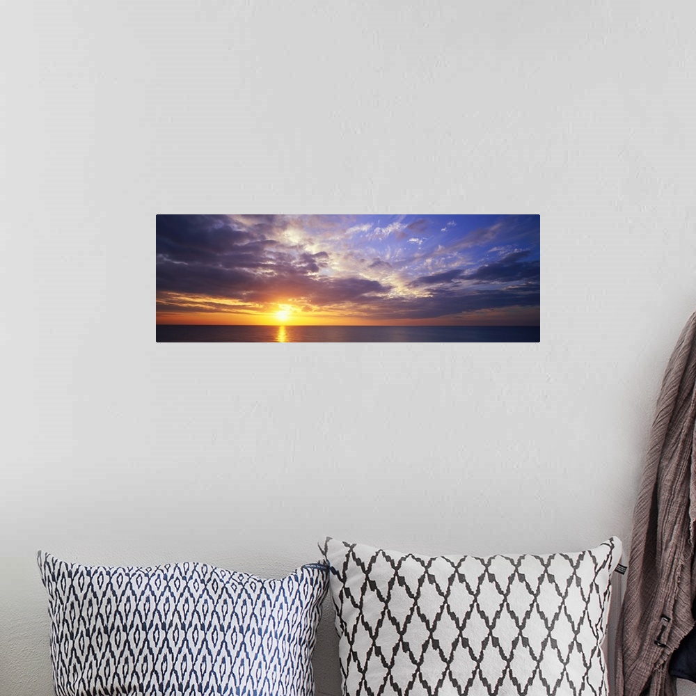 A bohemian room featuring This large panoramic picture was taken of a sunset about to hit the horizon over the ocean with c...