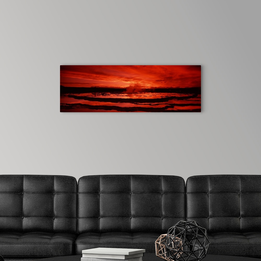 A modern room featuring Large canvas photo art of steam coming off a geyser silhouetted against a warm sky.