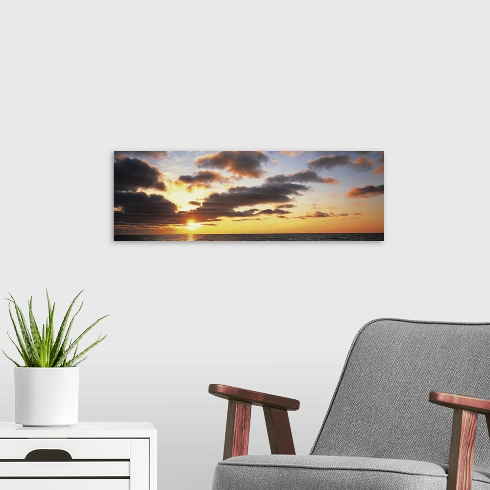 A modern room featuring Wide angle photograph of the sun setting slightly behind clouds, over the vast waters of Lake Mic...