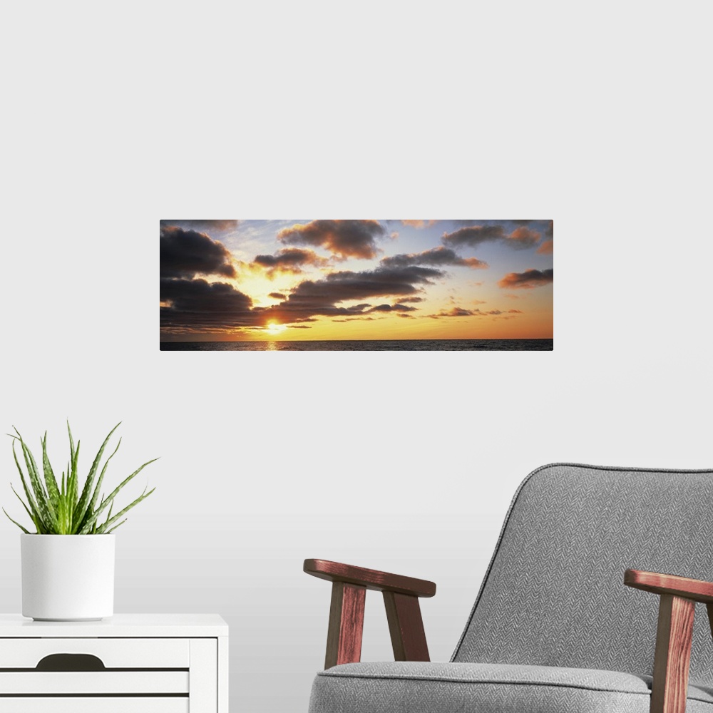 A modern room featuring Wide angle photograph of the sun setting slightly behind clouds, over the vast waters of Lake Mic...