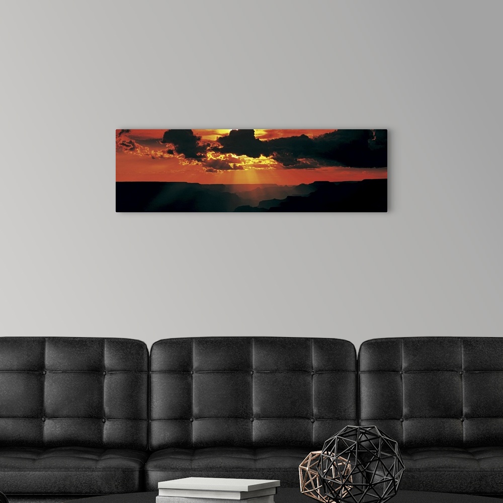 A modern room featuring Sun rays shine through thick clouds and silhouette the land below.