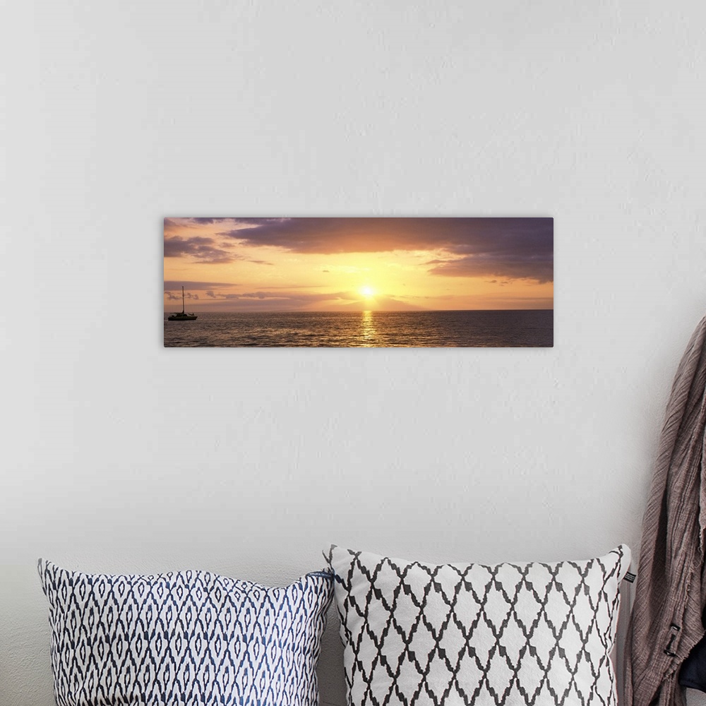 A bohemian room featuring Panoramic photograph on a large wall hanging of a single boat floating on rippling waters at suns...