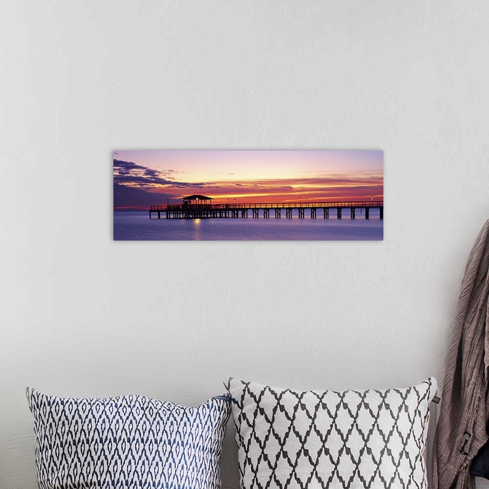 A bohemian room featuring Wide angle photograph of Mobile Pier surrounded by deep purple waters beneath a vibrant sunset, i...
